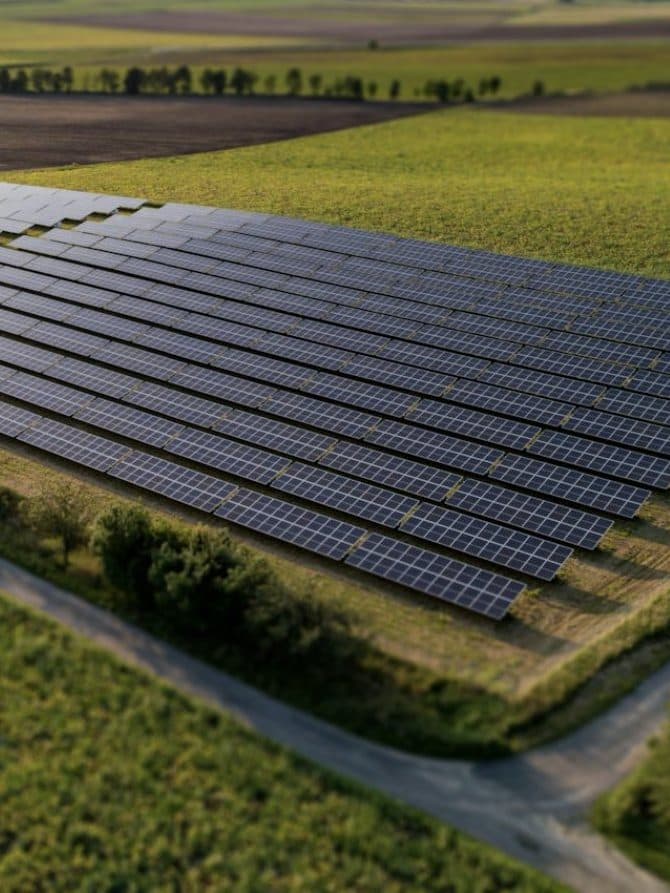 A solar power plant among green fields, seen from above.